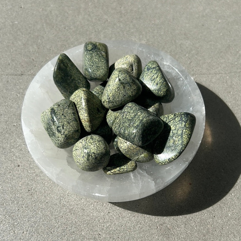 Serpentine tumbled stones in a bowl, ideal for meditation and spiritual healing.