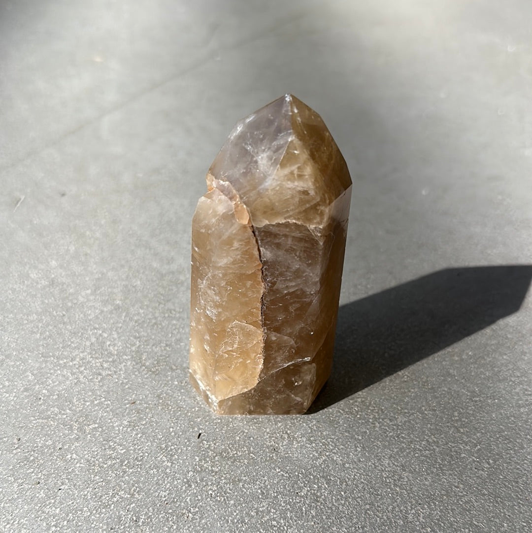 Citrine Tower crystal on a gray surface, promoting wealth, joy, and enhanced intuition.