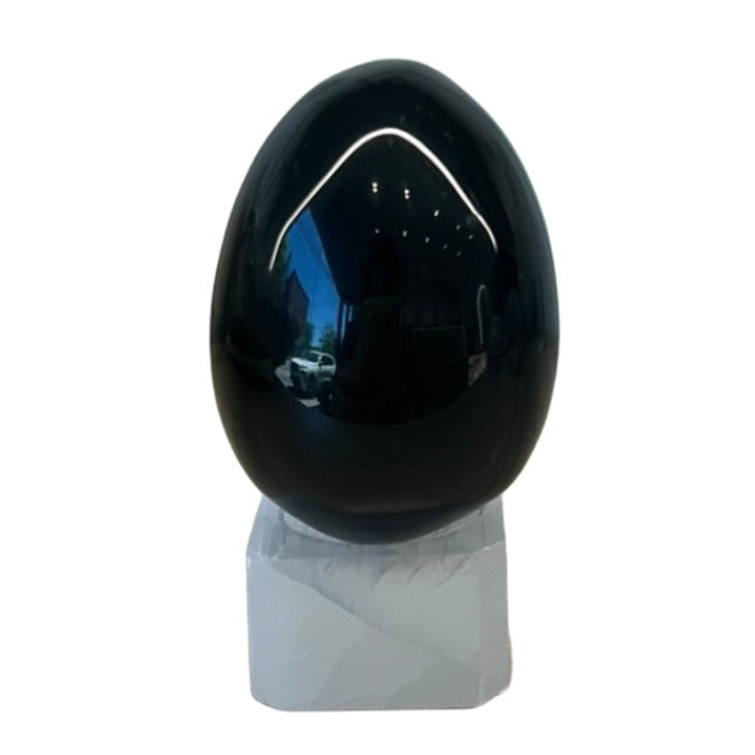 Obsidian egg on a marble base, approx 1.7", known for protection against negativity and promoting mental clarity.