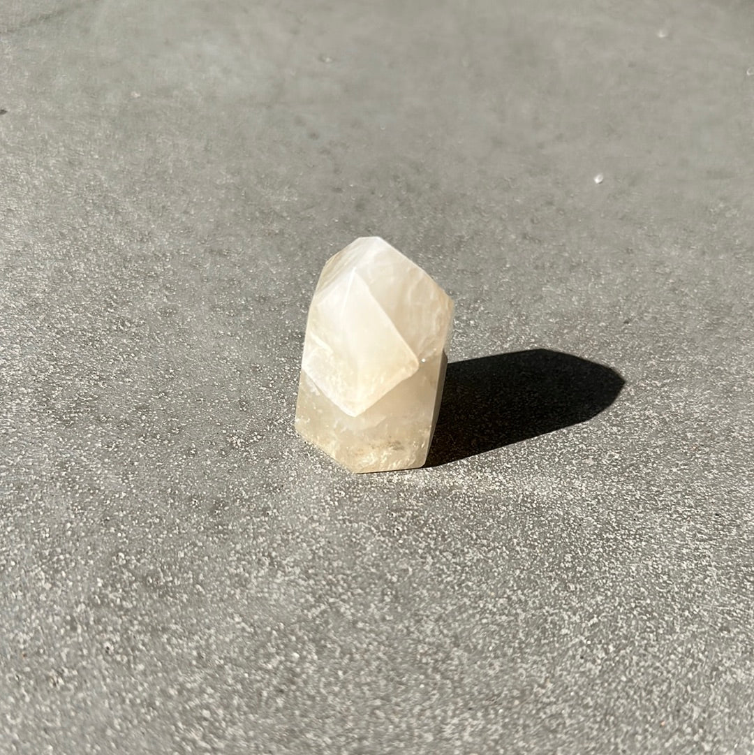Citrine tower crystal on a textured surface, known for enhancing intuition and attracting prosperity.
