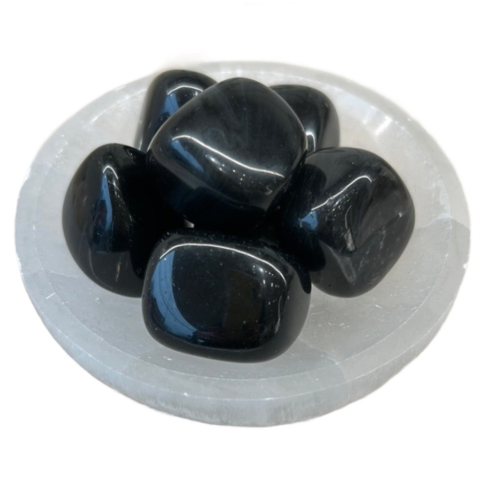 Tumbled Rainbow Obsidian stones on a crystal plate, promoting emotional healing and spiritual connection.