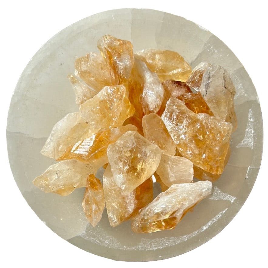 Raw citrine crystal points arranged on a white surface, showcasing their natural golden hues and energizing properties.