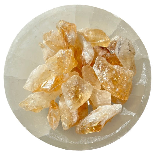 Raw citrine crystal points arranged on a white surface, showcasing their natural golden hues and energizing properties.