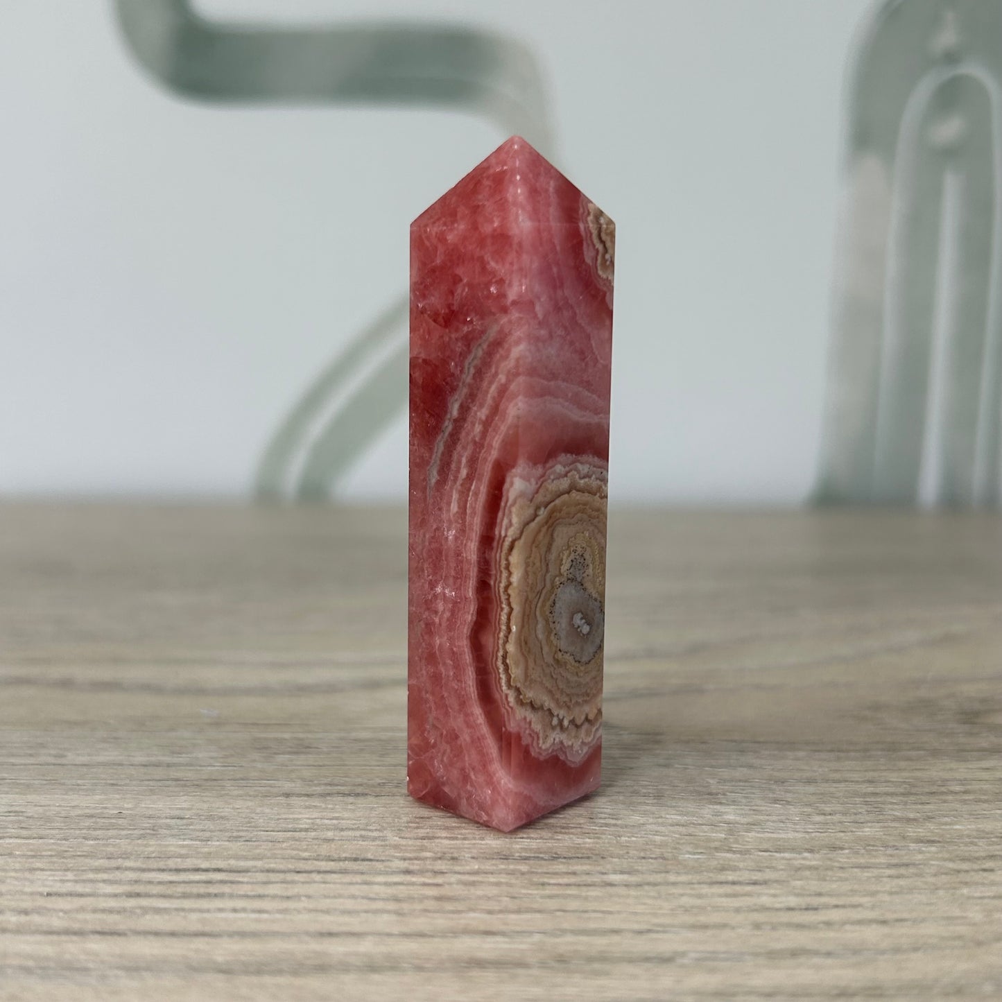 Rhodochrosite tower gem, 50g, promotes heart healing, positive mindset, and emotional balance, displayed on a wooden surface.