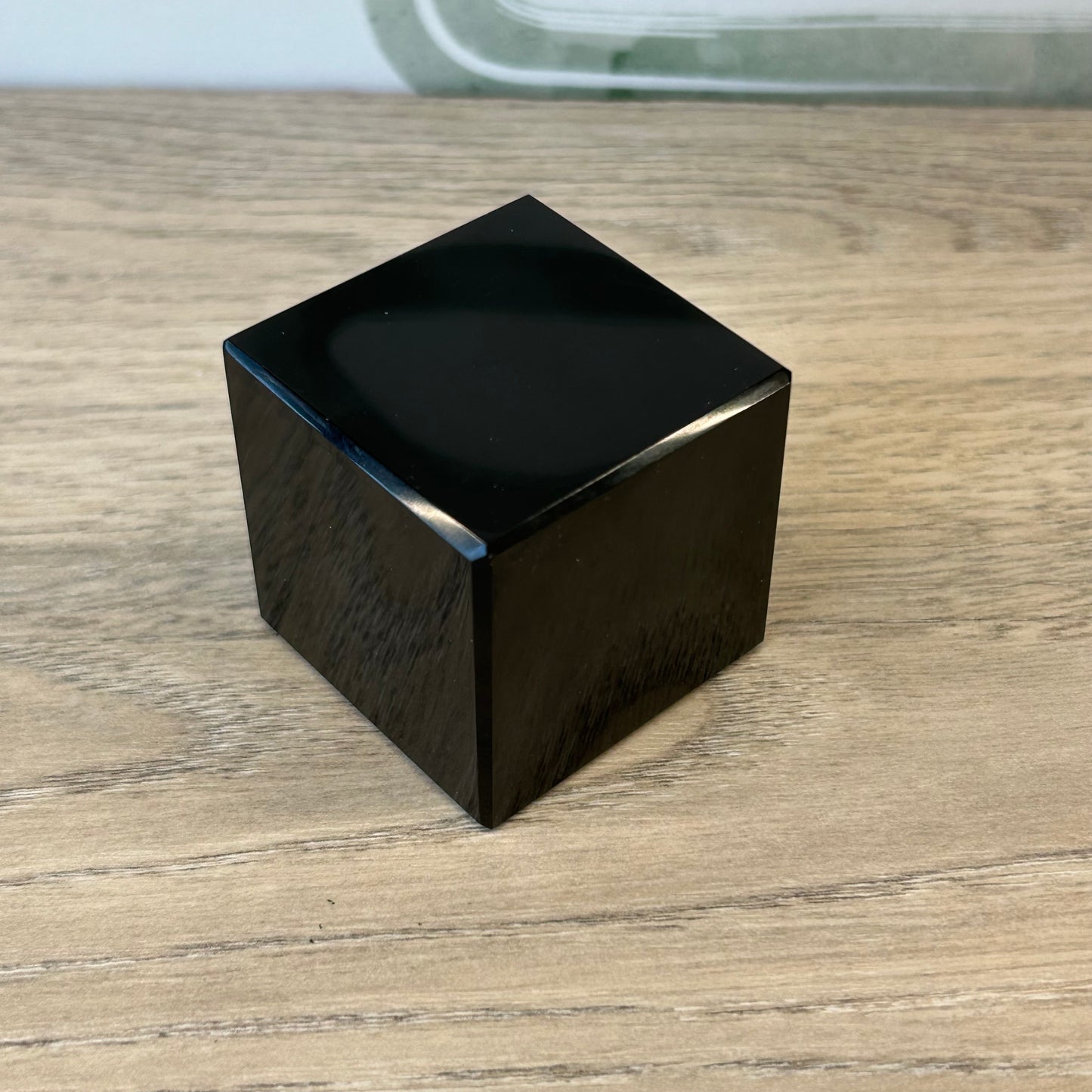 Black obsidian cube, approx 1.7”, known for protection against negativity and promoting mental clarity.