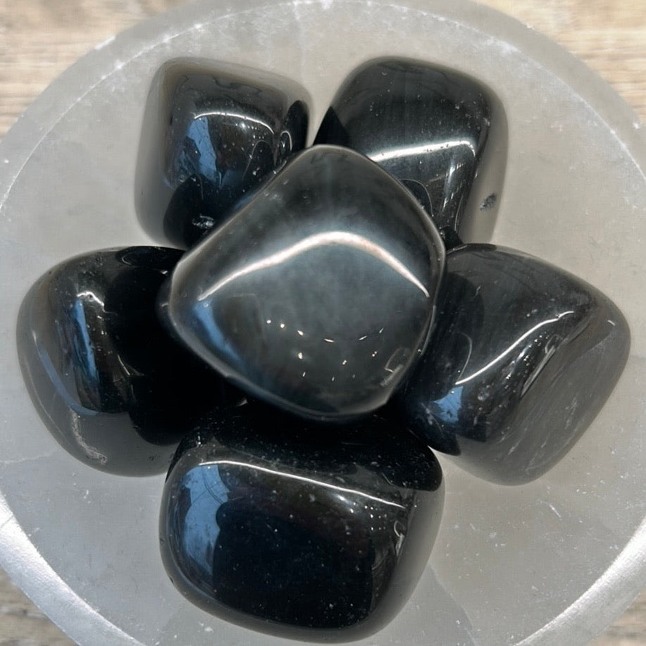 Rainbow obsidian tumbled stones arranged in a circular display on a crystal base.