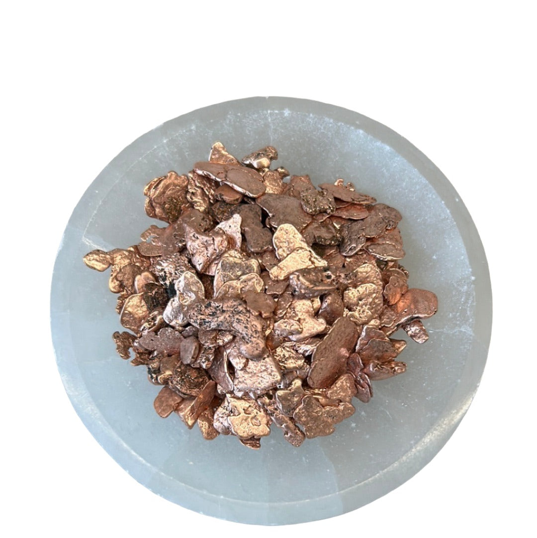 Copper nuggets on a round stone plate for energy healing and luck enhancement.