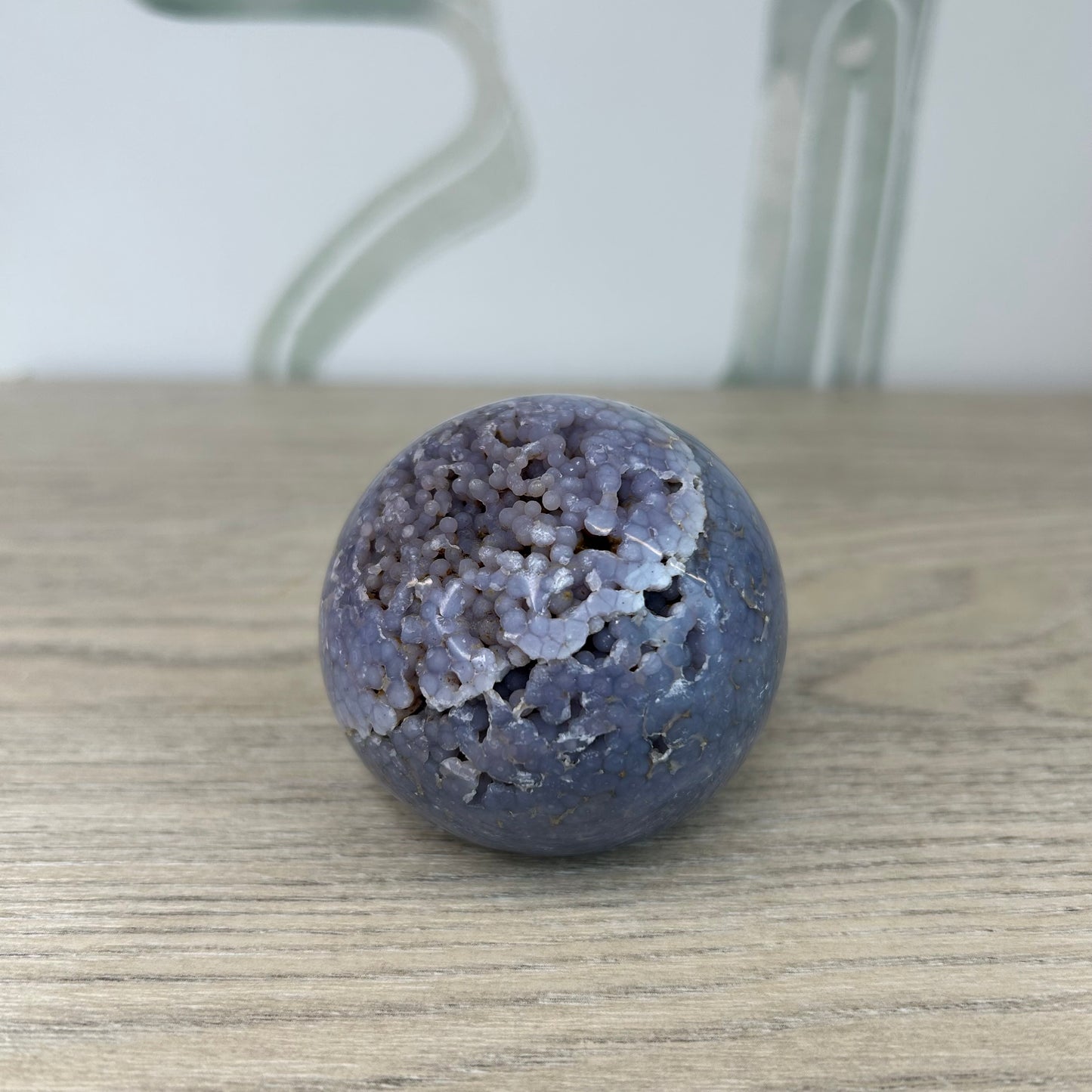 Grape agate sphere 233g on wooden surface, promotes inner stability, calmness, and emotional balance with unique gemstone design.