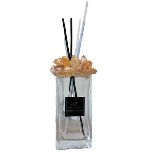 Citrine diffuser with black and clear reeds topped with natural citrine crystals in a stylish glass container.