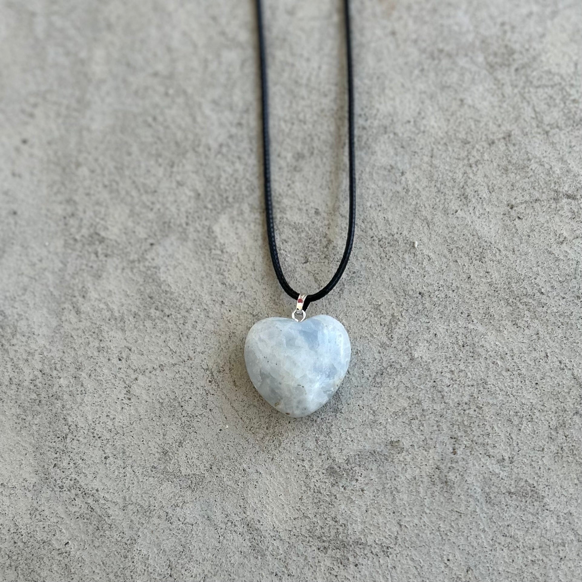 Blue Calcite heart pendant necklace on a black cord, promoting healing and clear communication energy.