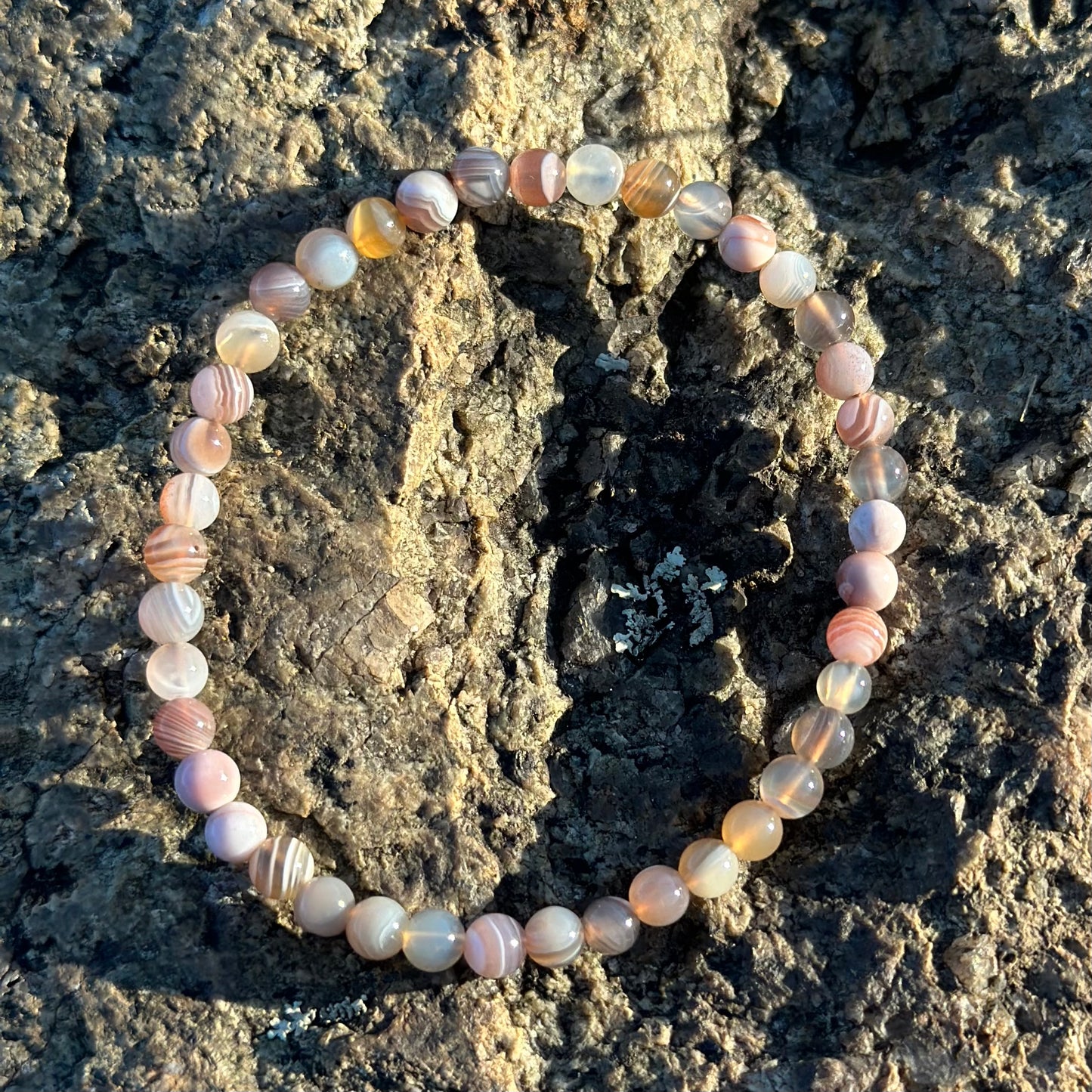 Botswana Agate Bracelet 4MM with healing beads displayed on textured rock background.