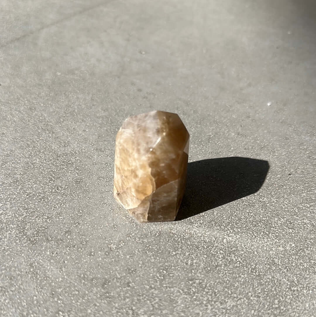 Citrine Tower crystal on a gray surface, promoting energy, wealth, and self-confidence.