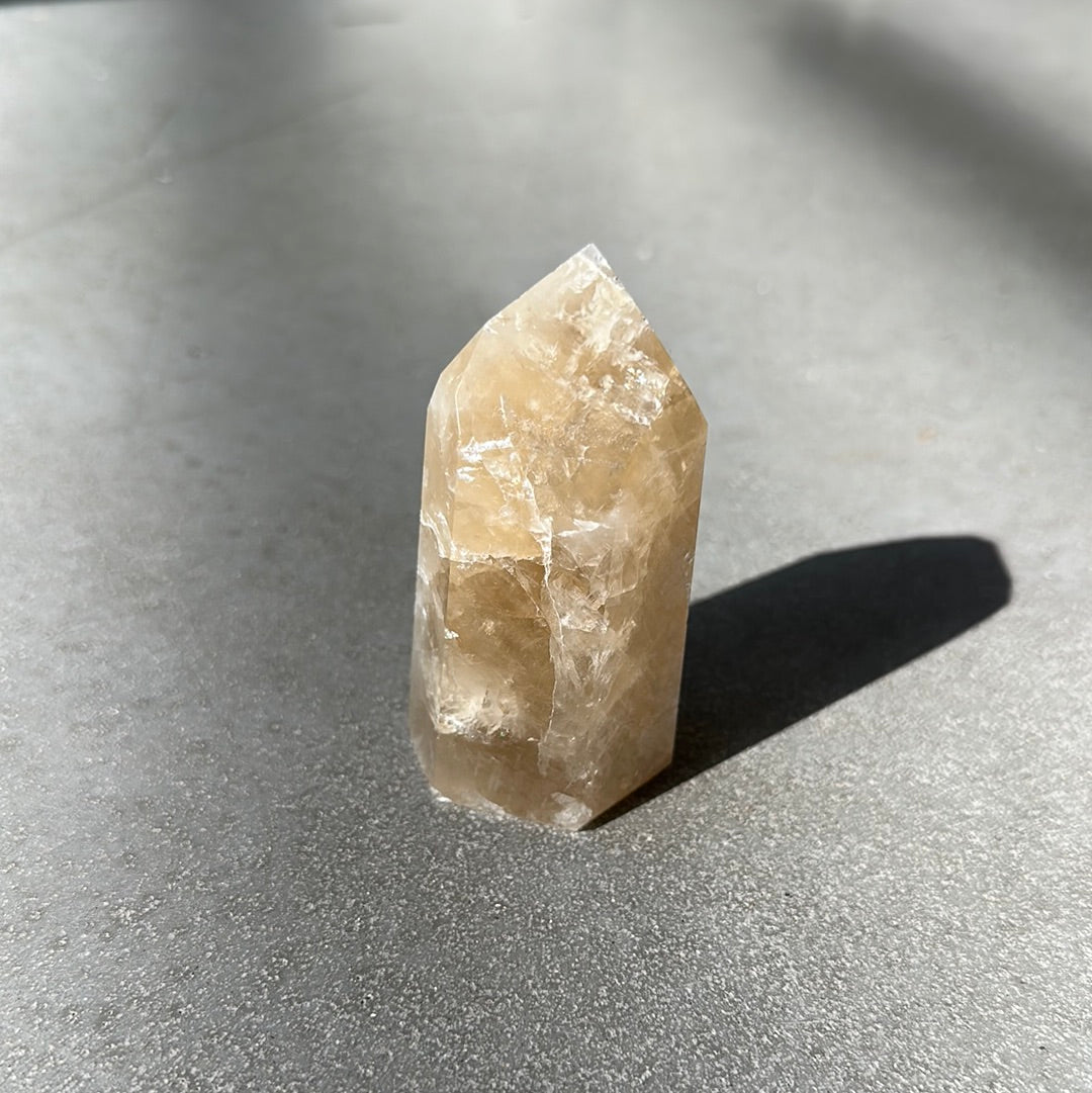 Citrine Tower crystal on a dark surface, known for energizing life and attracting wealth and success.