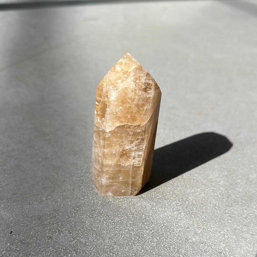 Citrine tower crystal standing on a light surface, known for attracting wealth and enhancing intuition.