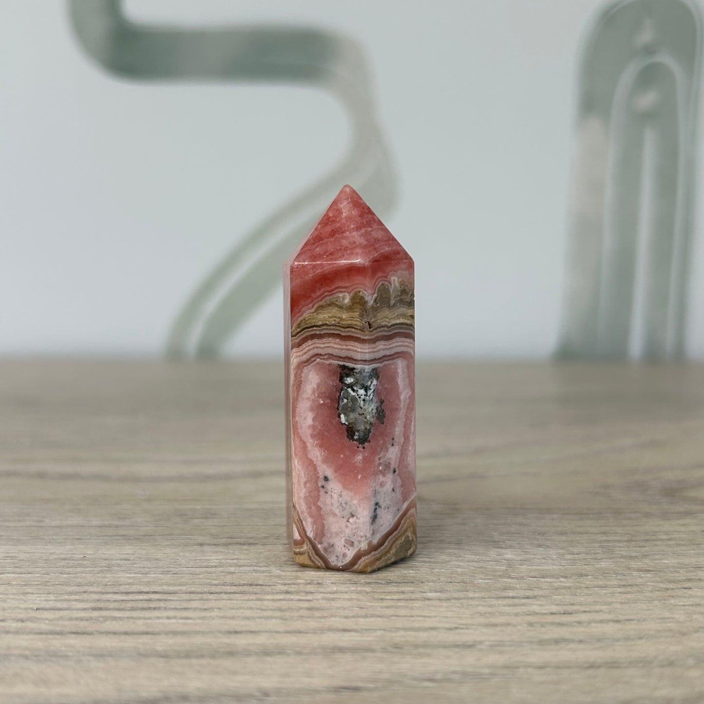 Rhodochrosite tower crystal on wooden surface, promoting heart healing and positive energy. Weight: 45g.