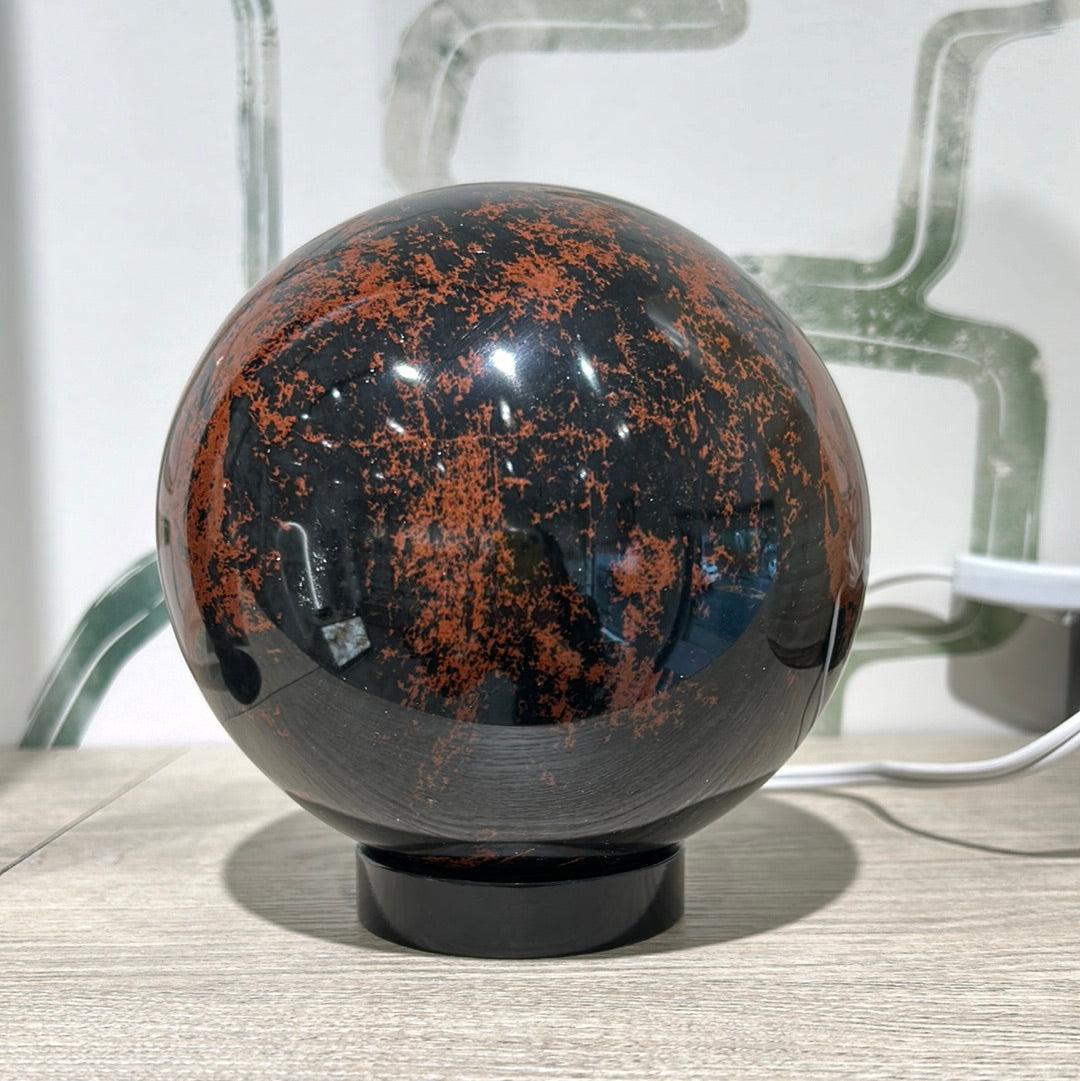 Mahogany obsidian sphere showcasing deep black and reddish-brown colors, ideal for promoting balance and well-being.