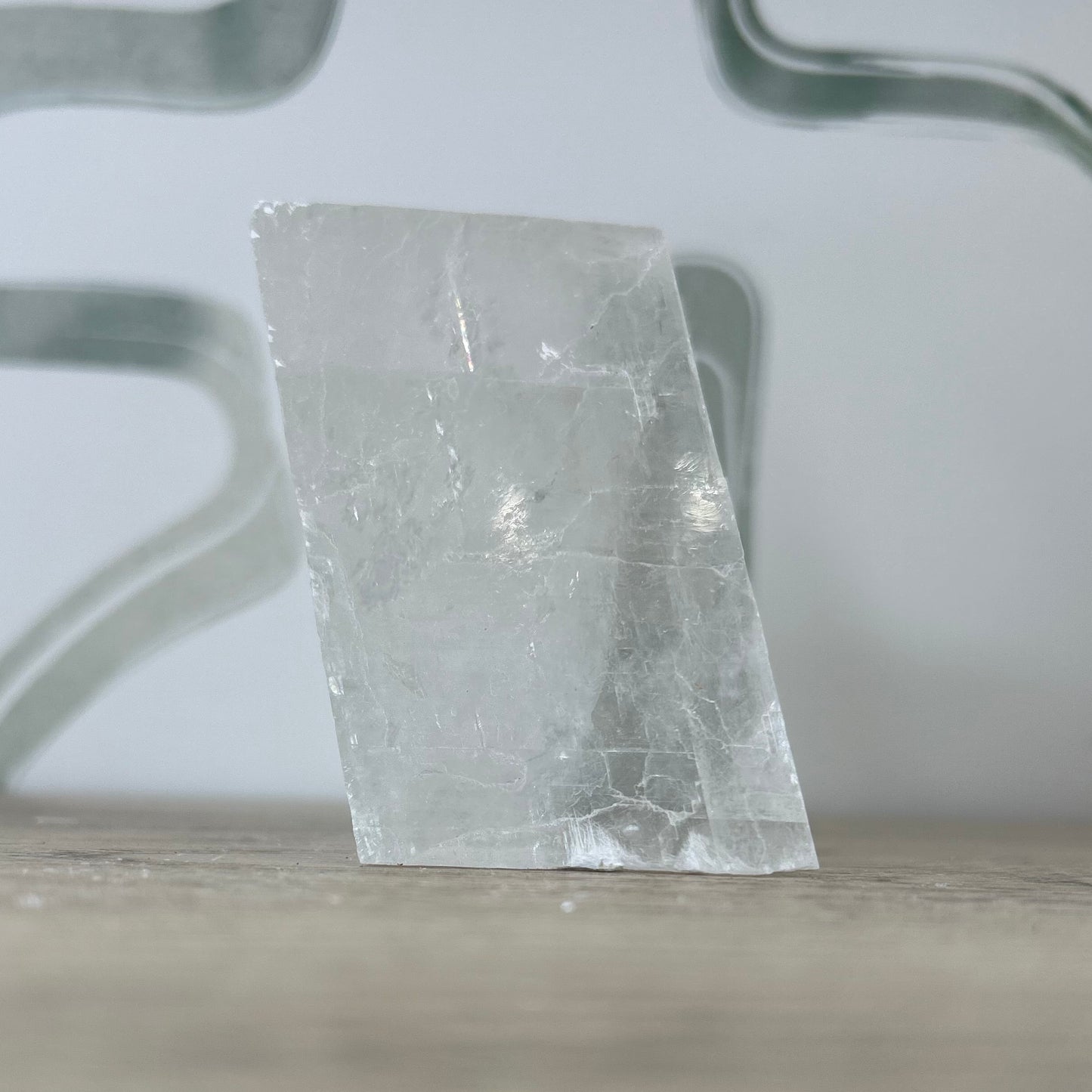Raw Optical Calcite Iceland Spar crystal on wood surface, perfect for healing and spiritual connection.