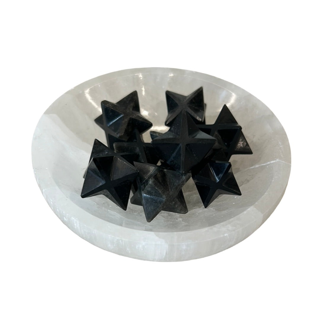 Black merkaba mini geometric shapes in a white stone bowl, showcasing their unique design and energy properties.
