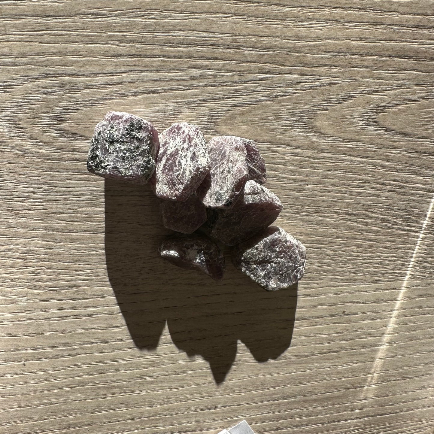 Ruby hexagon rough stones on wooden surface, showcasing natural texture and rich color variations.