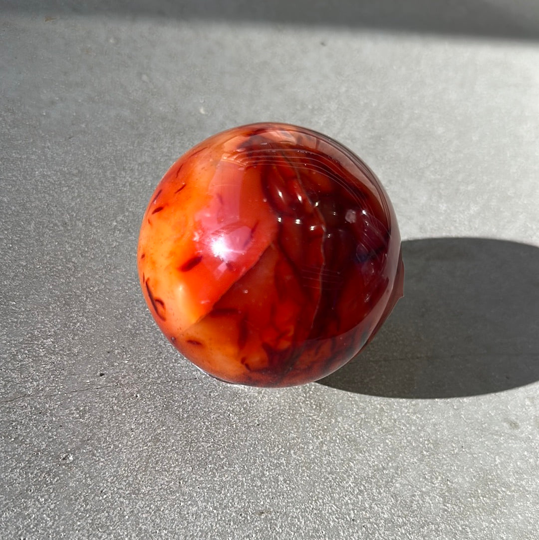 Carnelian sphere 487g, known for boosting creativity, vitality, and promoting positive life choices with vibrant colors.