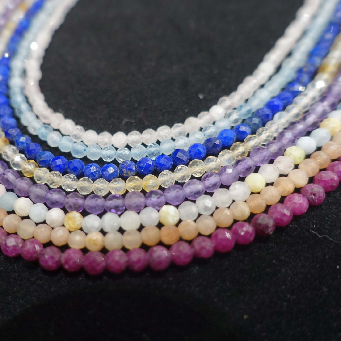 Colorful faceted gemstone bead strands displayed on a black background.