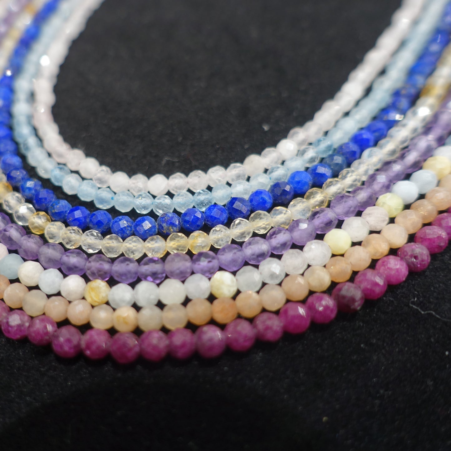 Multi-strand necklace with colorful faceted ruby beads on a dark background.