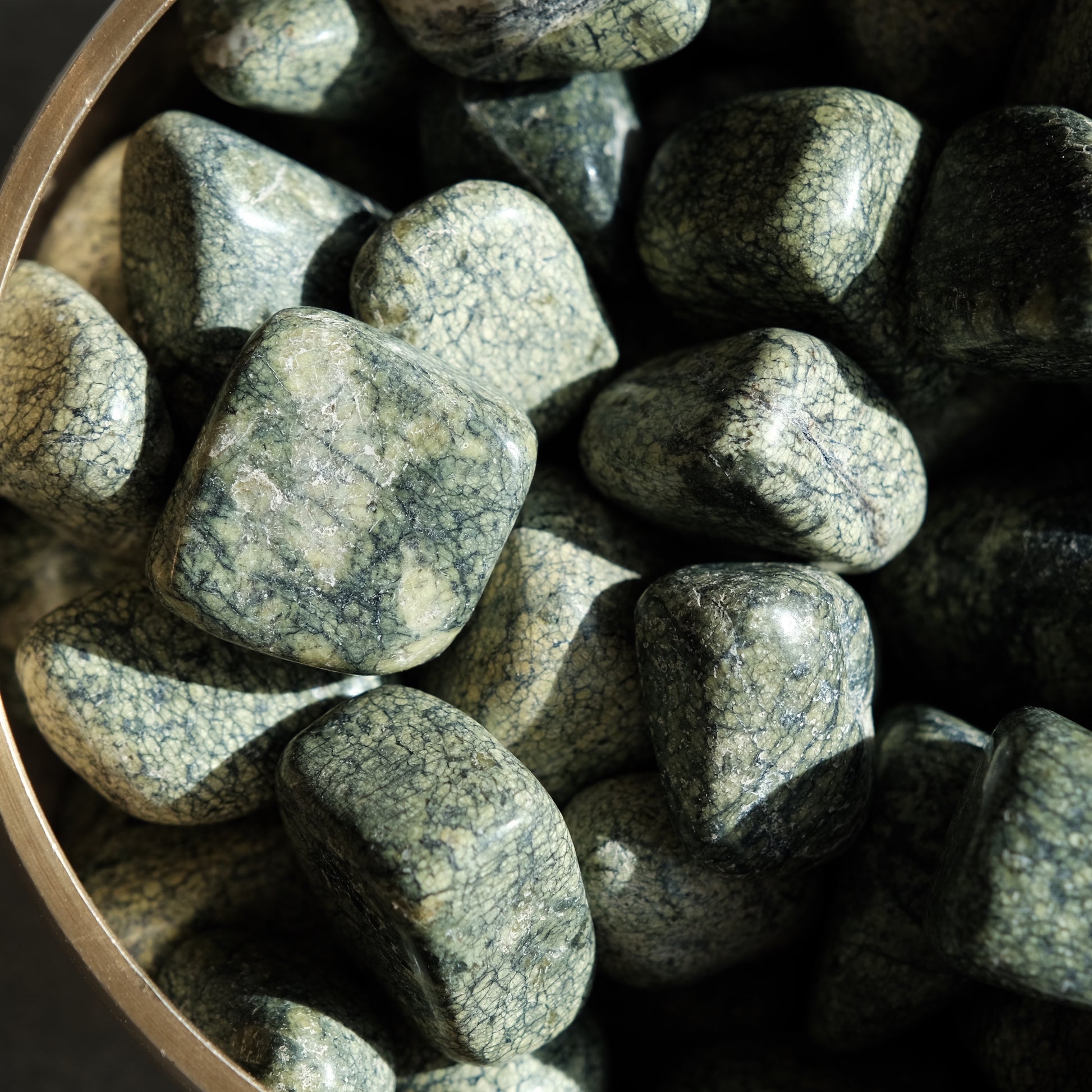 Serpentine tumbled stones in a bowl, ideal for meditation, healing energy, and balancing mental and emotional health.