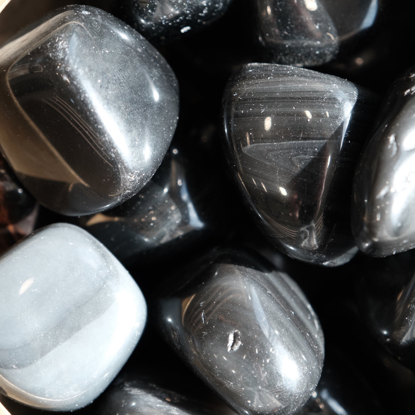 Rainbow Obsidian tumbled stones showcasing rich, dark colors, perfect for emotional healing and spiritual connection.