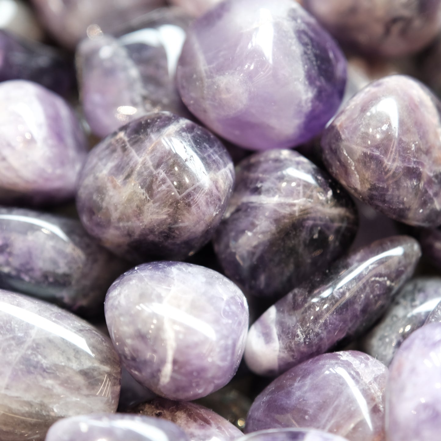 Close-up of polished amethyst tumbled stones in shades of purple for spiritual awareness and stress relief.