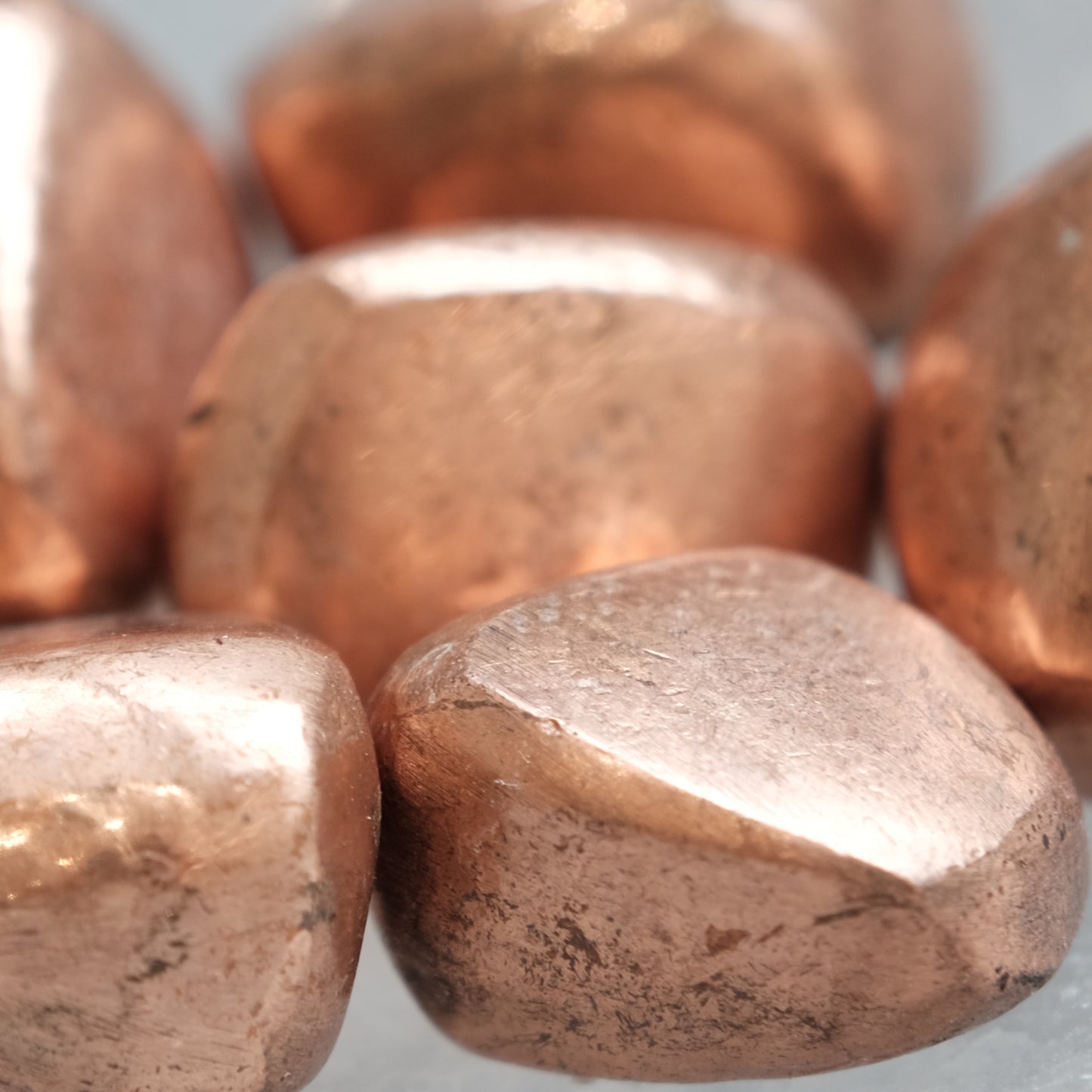 Copper tumbled stones close-up, known for enhancing energy, promoting optimism, and believed to bring luck in recovery of lost items.