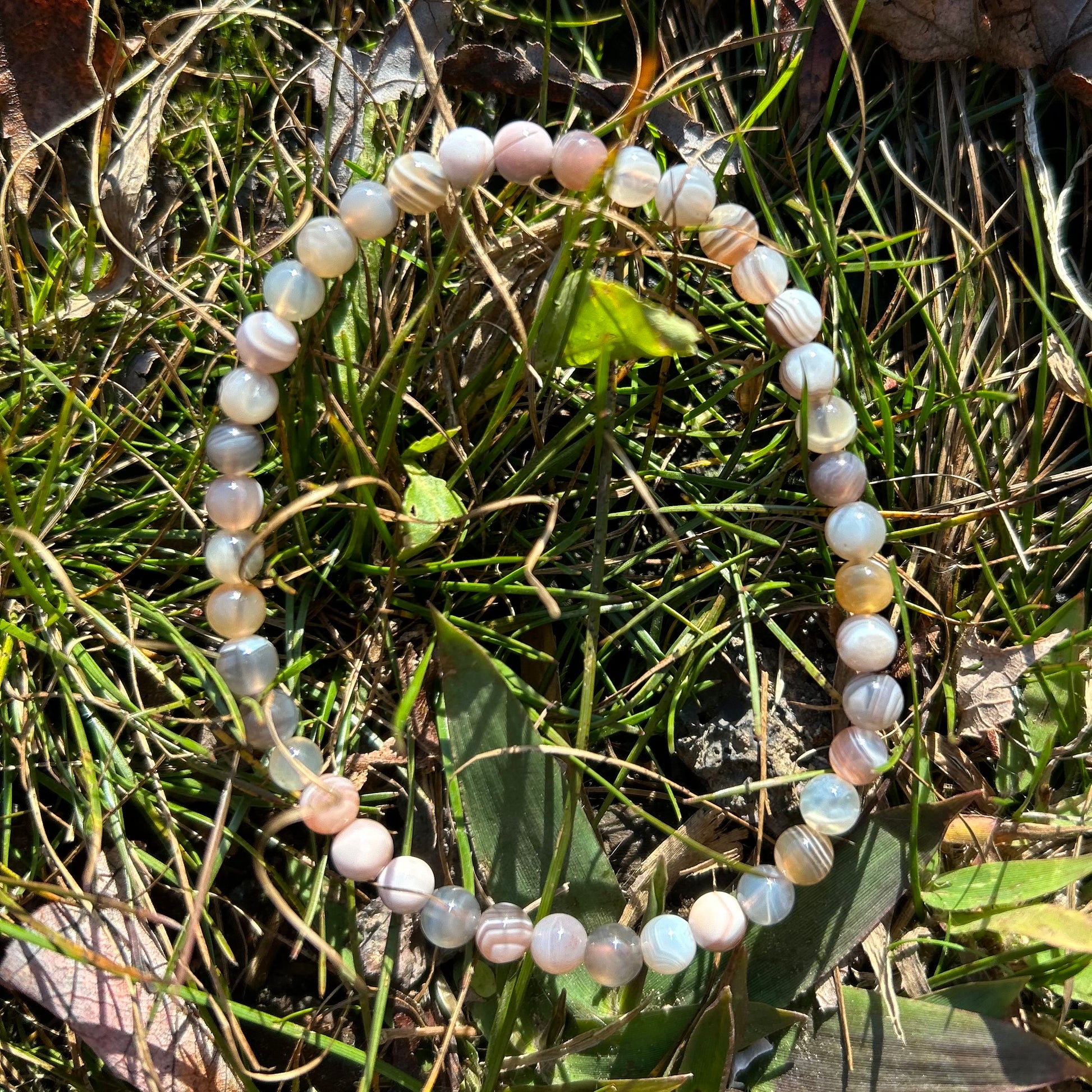 Botswana Agate Bracelet 4MM with healing properties resting on grass and leaves.