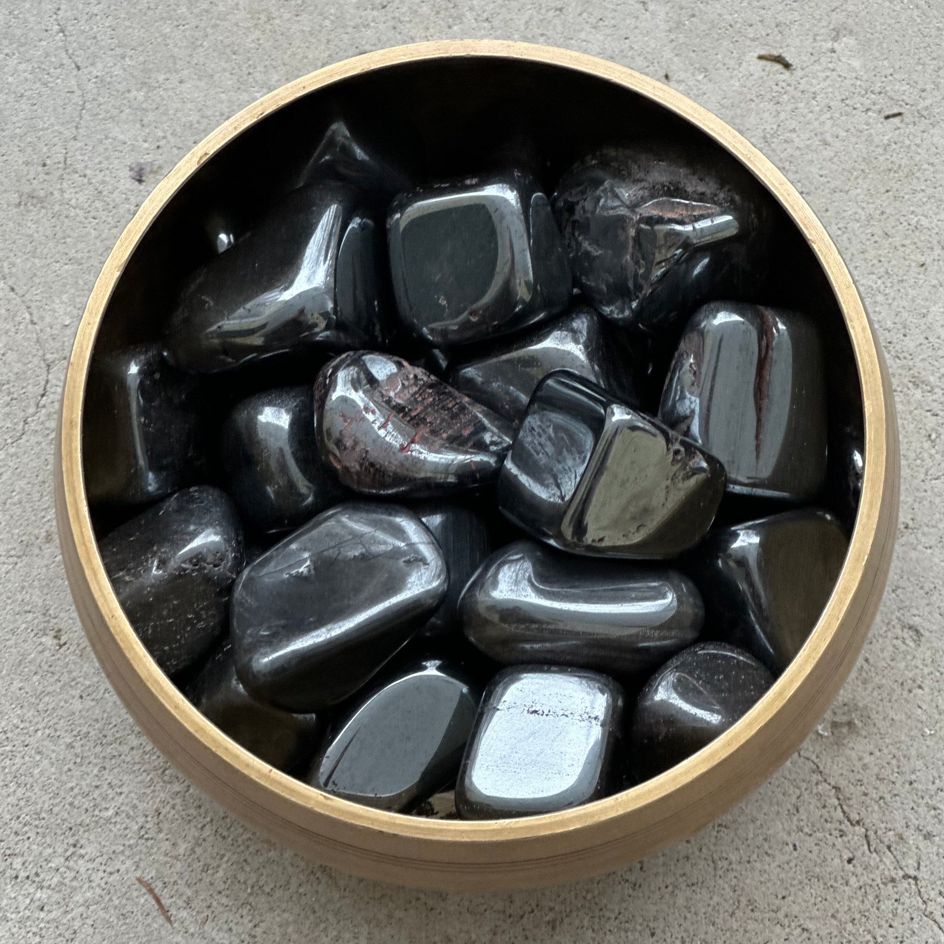 Hematite tumbled stones in a wooden bowl, showcasing grounding and protective energy properties for focus and clarity.