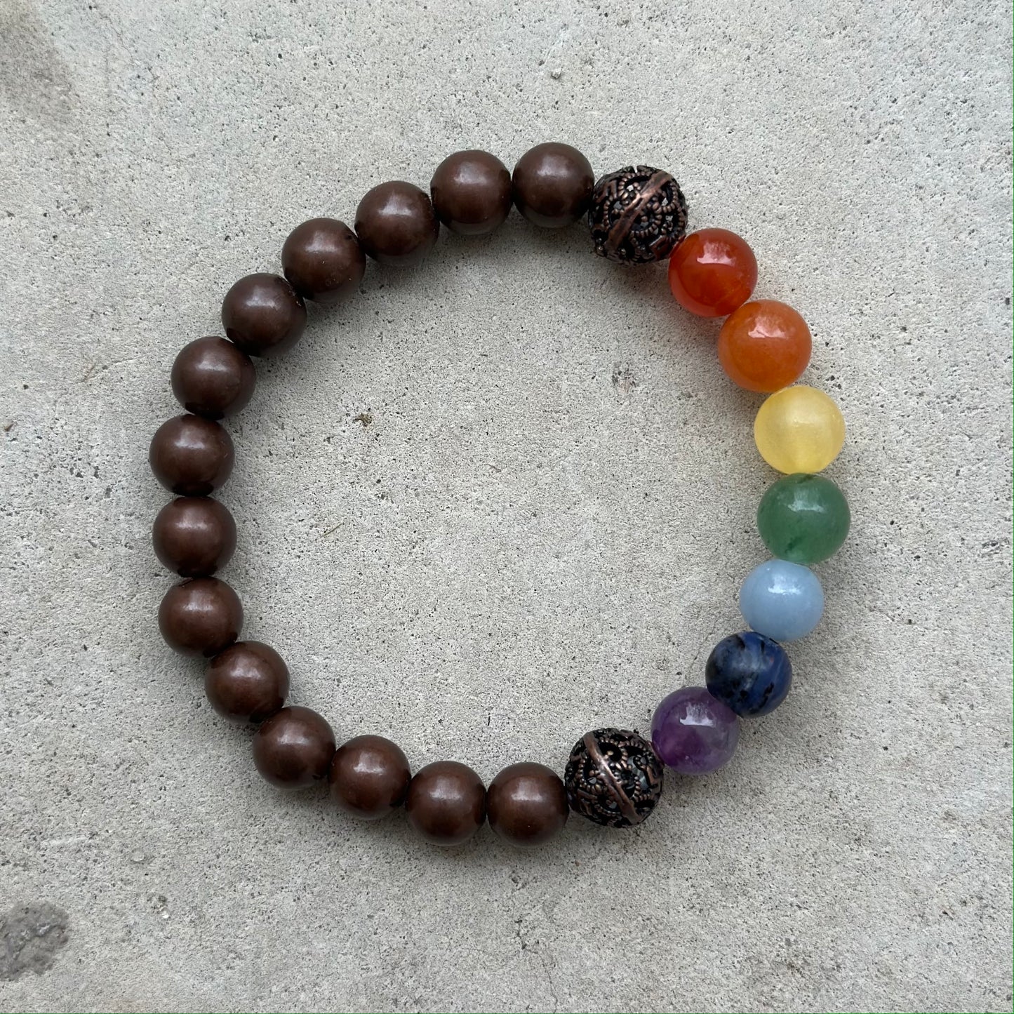 Handcrafted copper bracelet with colorful chakra stones enhancing energy and promoting healing benefits on a neutral background.