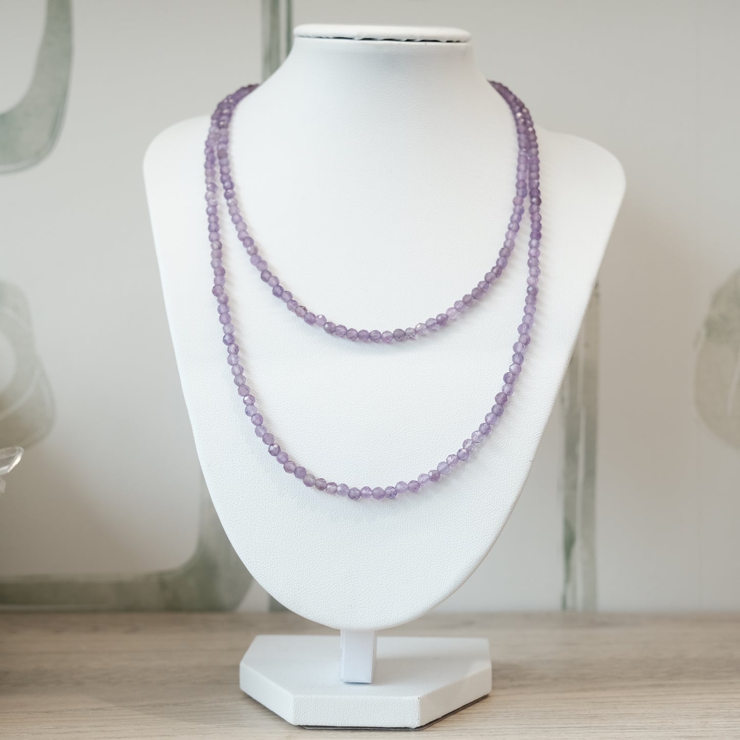 Amethyst faceted 31" necklace displayed on a stand, multi-wrap bracelet option, 3mm beads, soothing and stress-relieving properties.