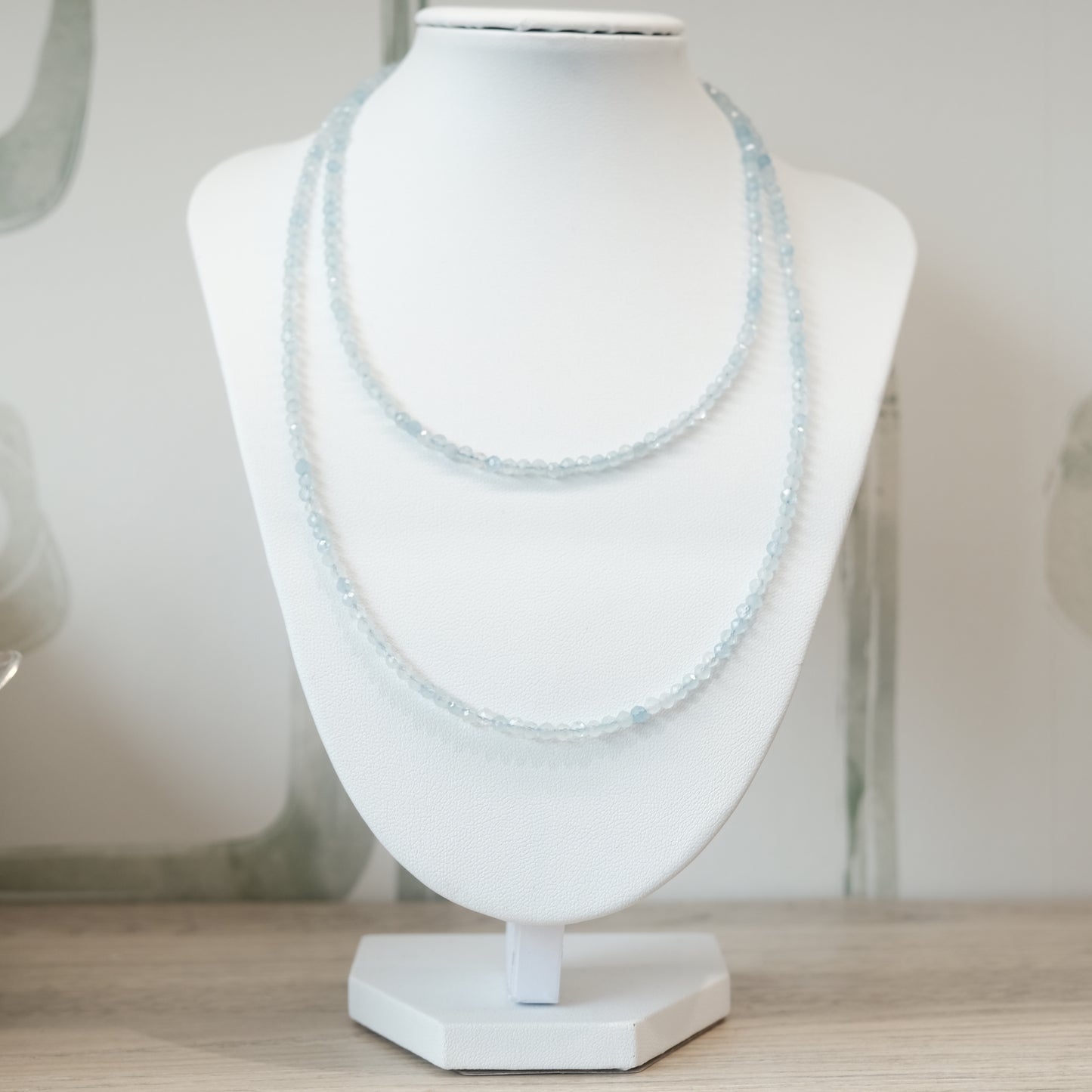 Aquamarine faceted 31" necklace on display stand, versatile as multi-wrap bracelet, promotes calmness and reduces stress.