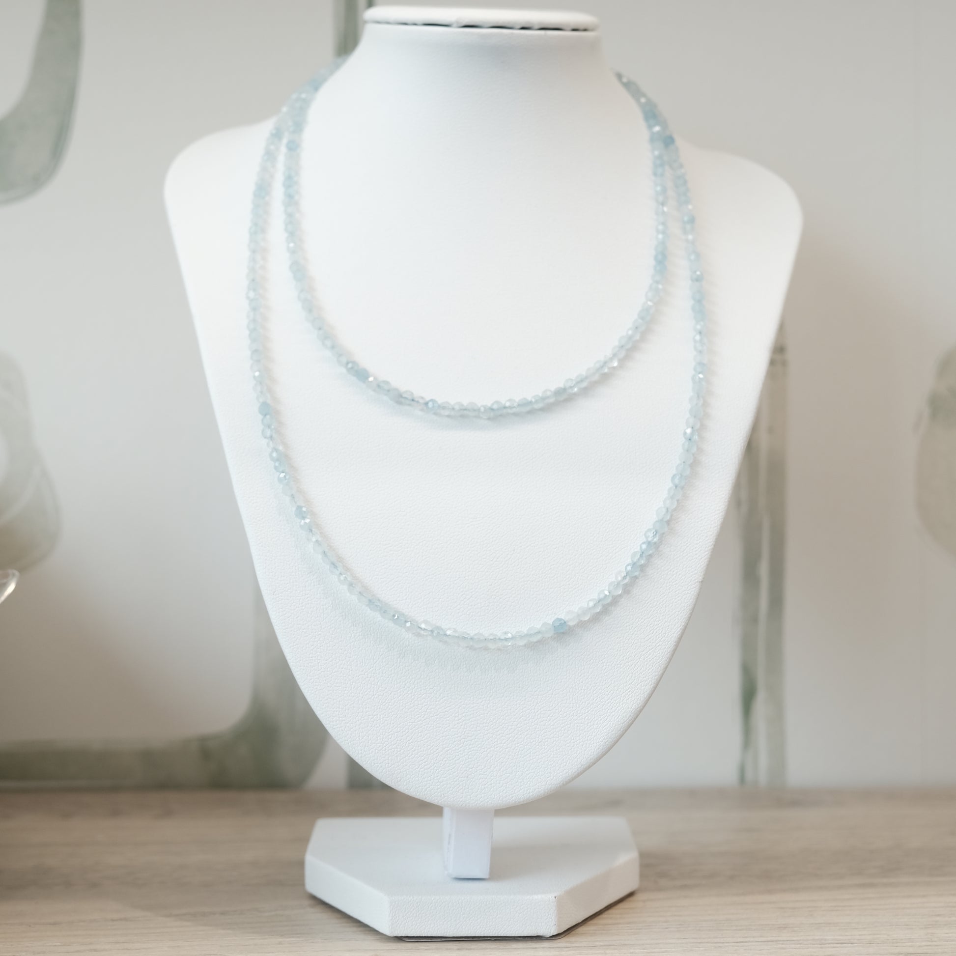 Aquamarine faceted 31" necklace on display stand, versatile as multi-wrap bracelet, promotes calmness and reduces stress.