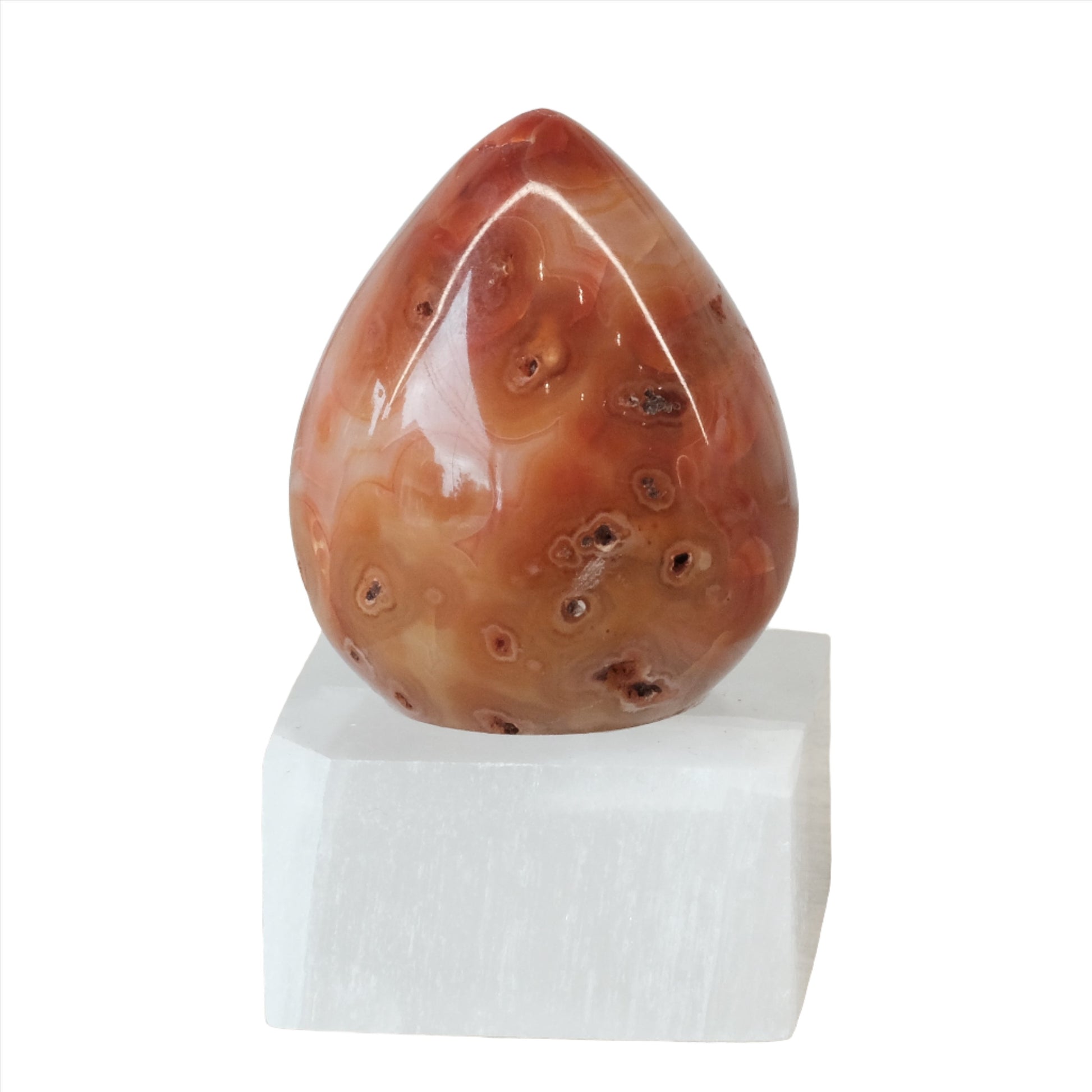 Carnelian egg on a white base, known for restoring vitality, creativity, and promoting positive life choices.