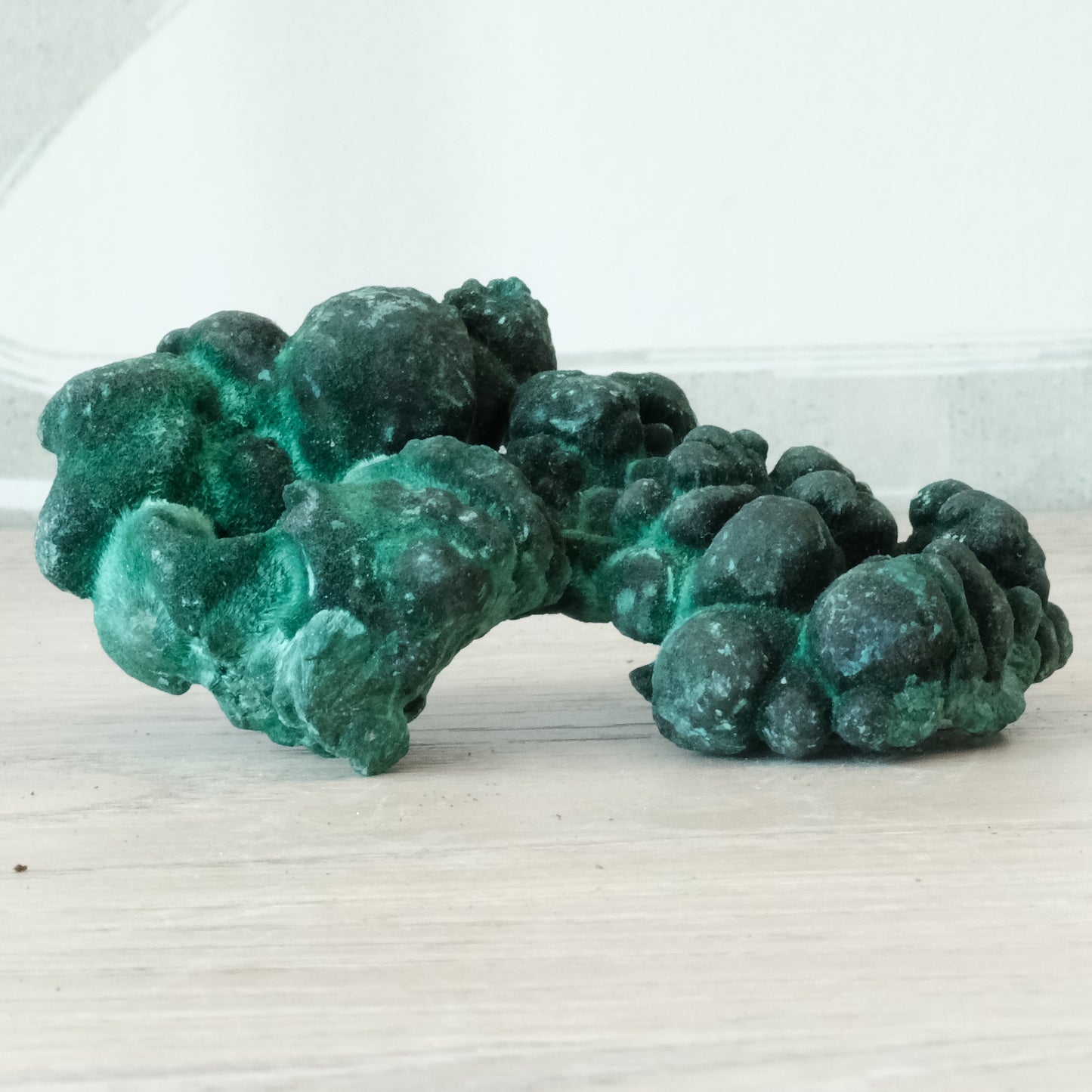 Natural 70g malachite gemstone with vibrant green hue, known for detoxifying and healing properties, placed on a wooden surface.