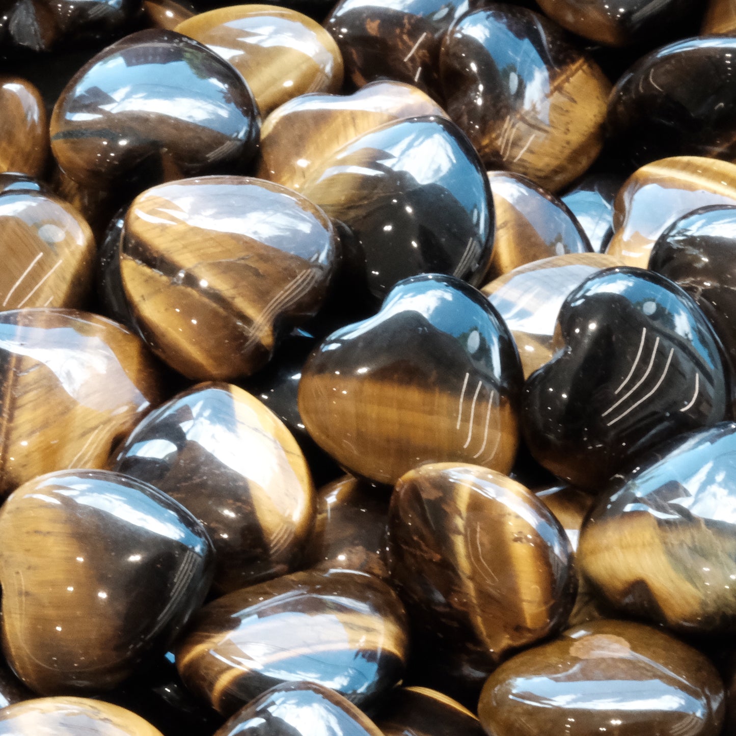 Glossy tiger eye heart stones with iridescent gold and bronze hues, symbolizing grounding and protection.