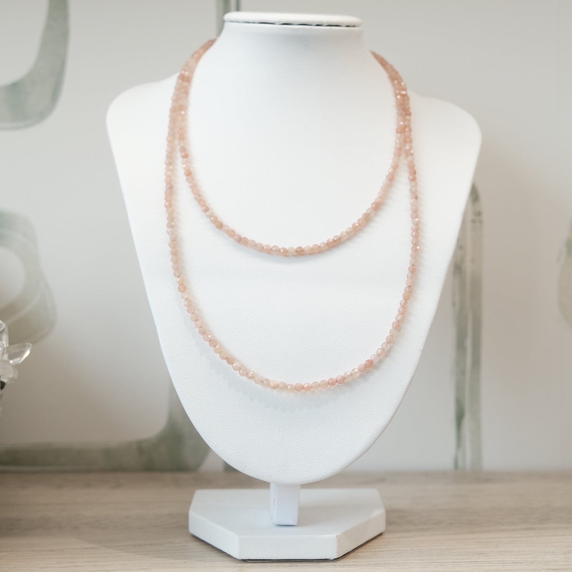 Peach Moonstone Faceted 31" Necklace and Multi Wrap Bracelet on a display bust, showcasing its elegant and delicate design.