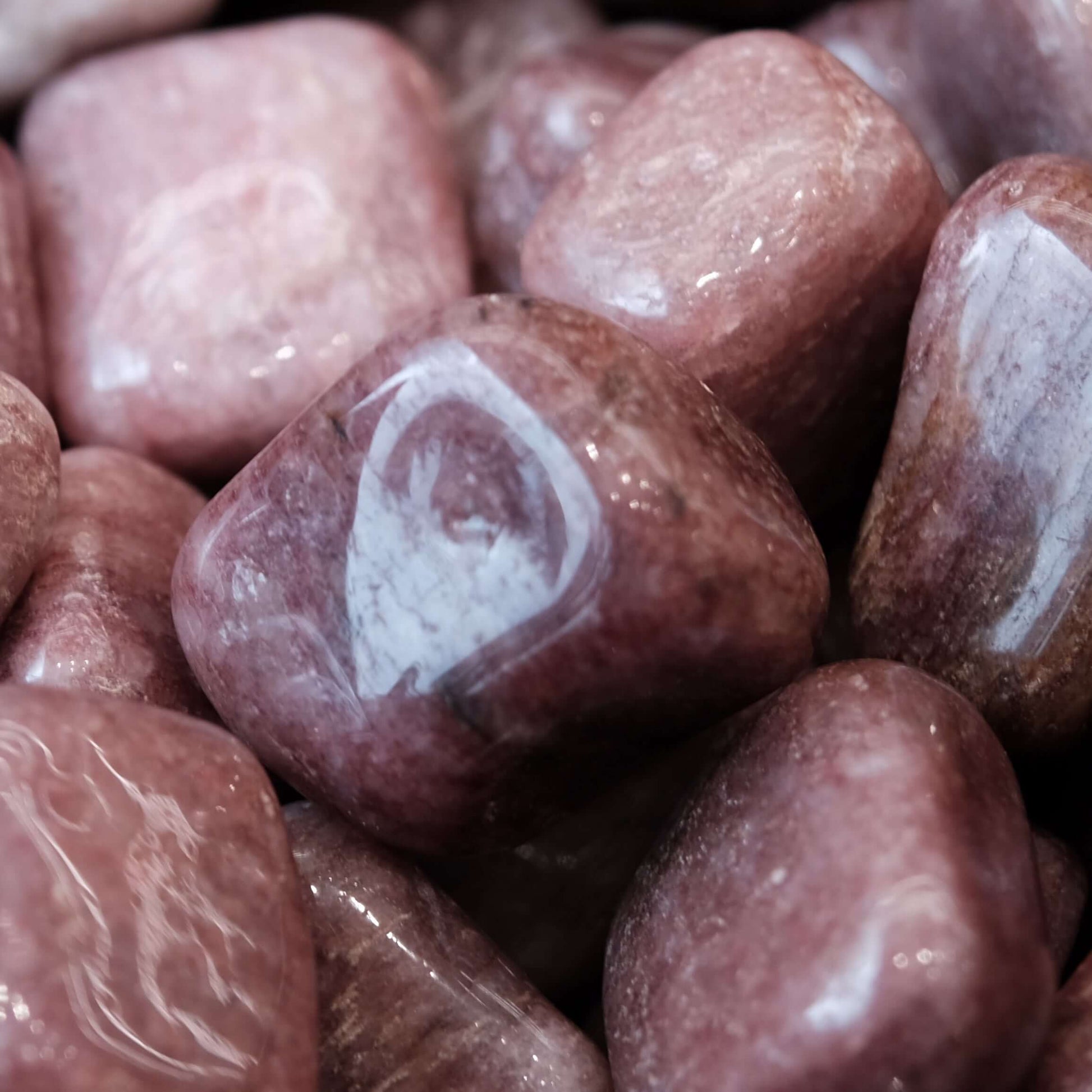 Tumbled strawberry quartz stones with pink hues and unique mineral inclusions promoting healing and emotional balance.
