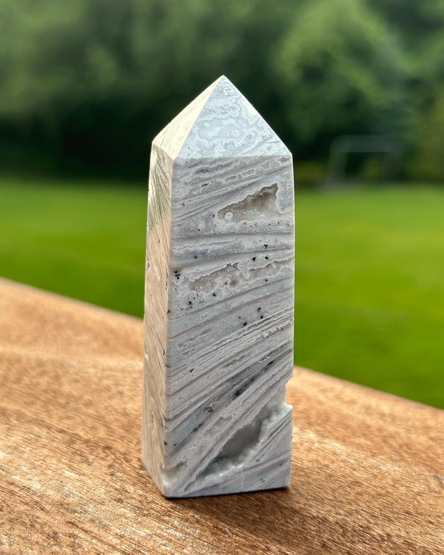 White Lace Agate Tower with unique patterns and calming energy, ideal for home decor and stress reduction, outdoors on a wooden surface.