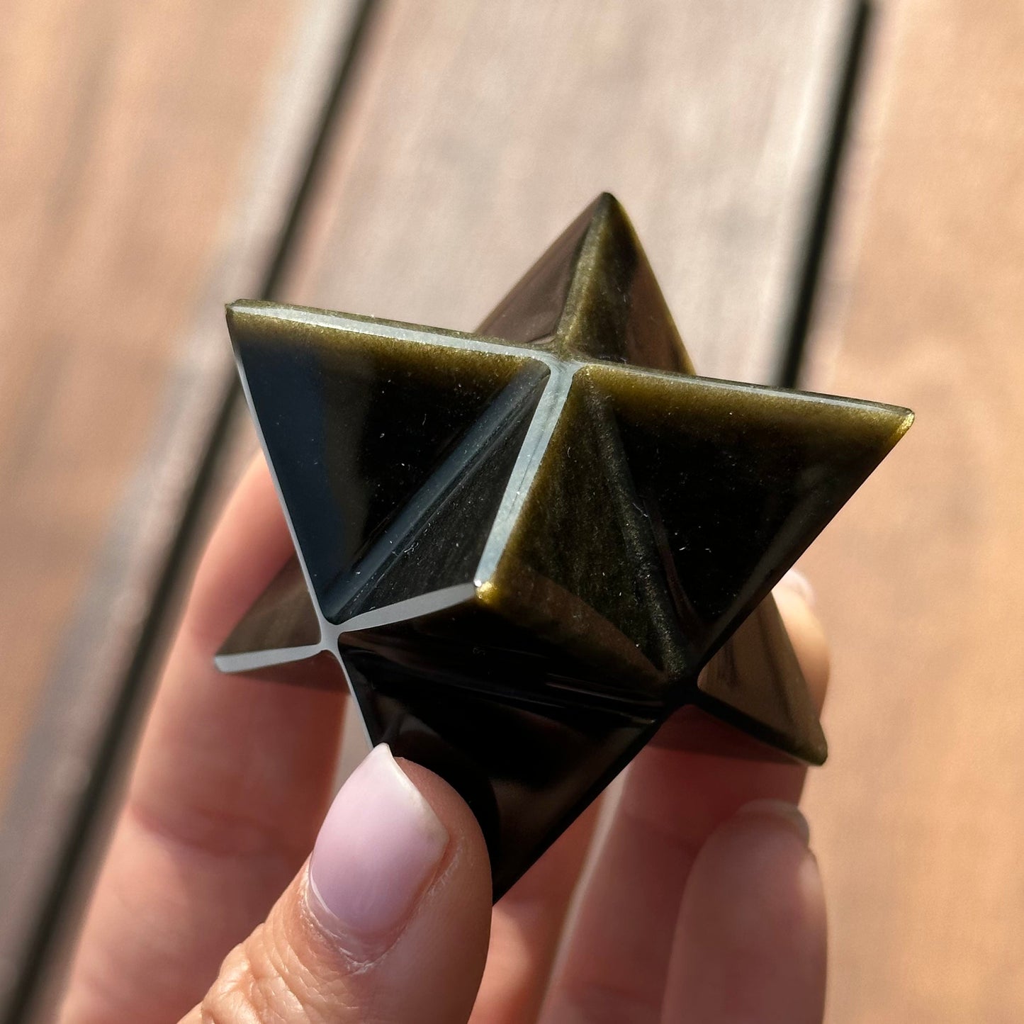 Golden sheen obsidian Merkaba crystal held in hand, showcasing its unique geometric design and rich color.