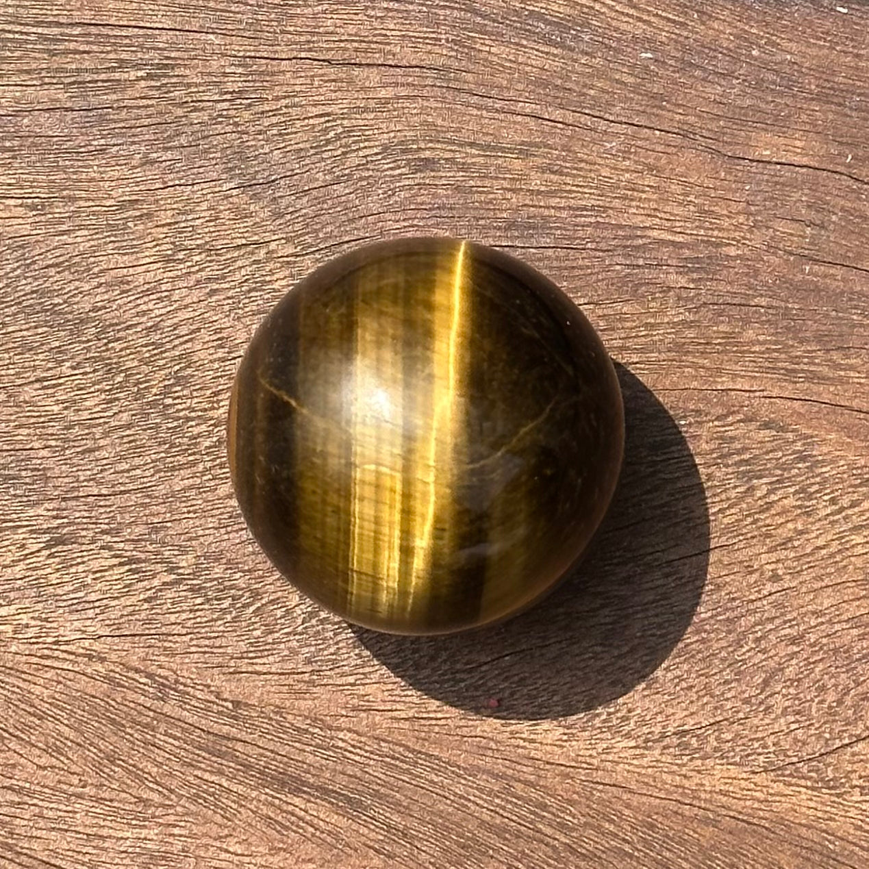 Tiger Eye sphere polished stone, promoting focus, protection, and healing for mind and body.