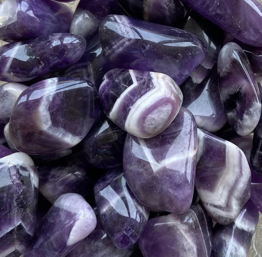 Polished purple amethyst stones showcasing natural patterns and hues, known for spiritual and emotional benefits.