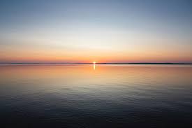 Serene sunset over calm ocean reflecting vibrant colors in a peaceful horizon.