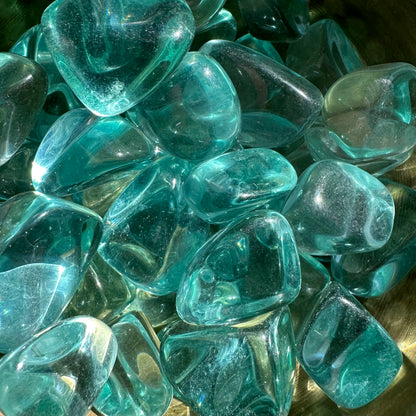 Aqua Obsidian tumbled stones with glassy texture, known for protective energies and throat chakra stimulation.