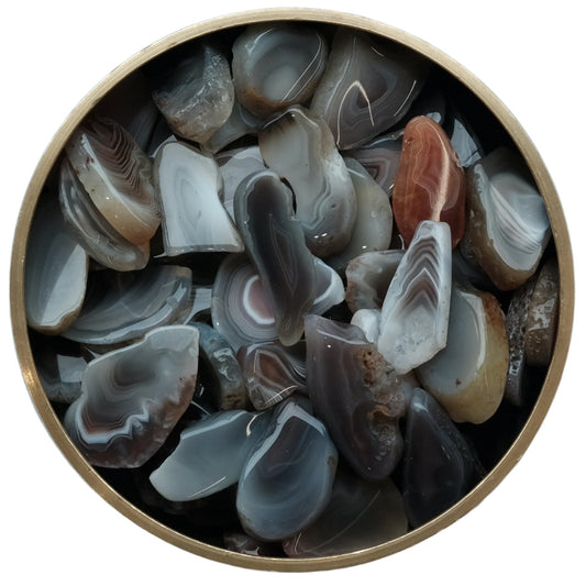 Collection of natural agate slices in a round container showcasing unique patterns and colors.