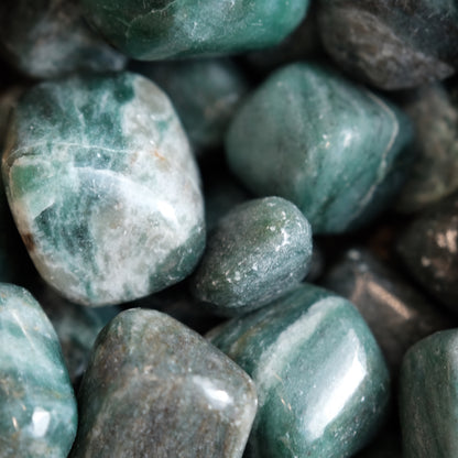 Close-up of emerald with fuchsite tumble stones, showcasing their green hues and smooth, polished surfaces for emotional healing.