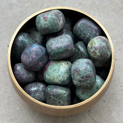 Bowl of Ruby Zoisite tumbled stones with green and red hues, promoting happiness and positive energy.